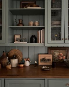 a kitchen with blue cabinets and pictures on the counter top in front of shelves filled with books