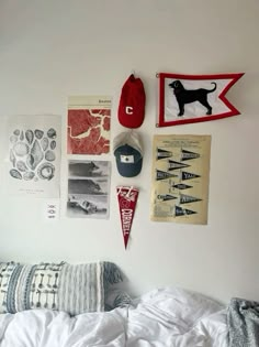 a bed with white sheets, pillows and pictures on the wall next to each other