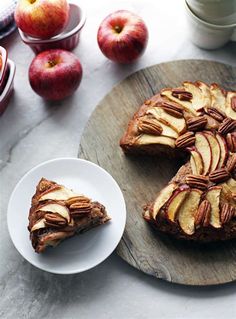 two slices of apple pie on a plate next to some apples and other fruit in bowls