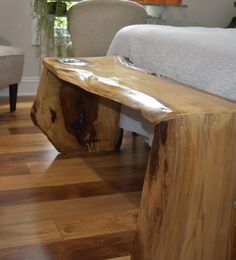 a wooden bench sitting on top of a hard wood floor next to a white bed