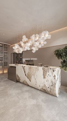 a large white marble counter sitting under a chandelier in a room next to a plant