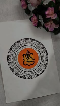 an orange and black sticker sitting on top of a piece of paper next to flowers