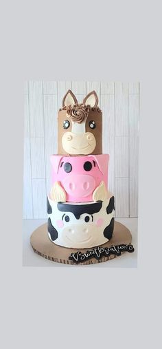 a three tiered cake with a cow on it's side, decorated in pink and black