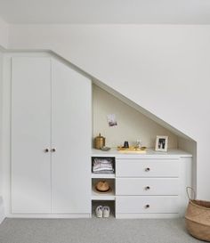 an attic bedroom with white cabinets and drawers