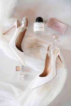 the bride's wedding shoes and jewelry are laid out on the white bed sheet