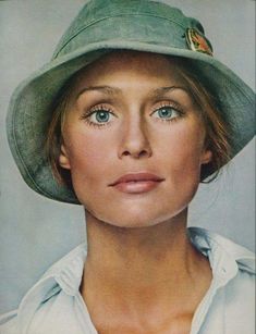 a woman wearing a green hat and white shirt with her eyes wide open to the side