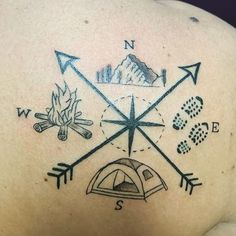 the back of a man's shoulder with an arrow and compass tattoo on it