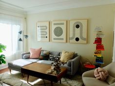 a living room filled with furniture and paintings on the wall above it's coffee table