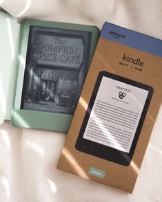 an amazon kindle sitting on top of a bed next to a book titled the pumpkin spice cafe