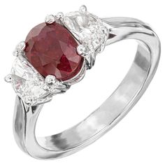 a red and white diamond ring with three stones on the band, set in 18k white gold