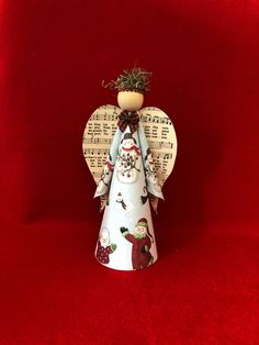 an angel figurine on a red background with sheet music and christmas decorations around it