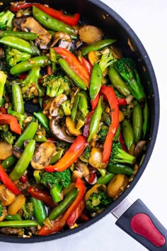 a pan filled with stir fry vegetables on top of a stove