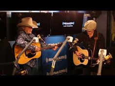 two people playing guitars in front of microphones