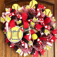 a softball wreath on the front door decorated with red, white and yellow ribbon bows