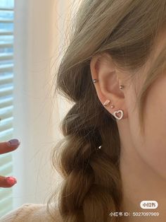 a woman is holding her hand up to her ear with two piercings on it