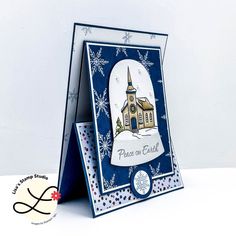 a christmas card with a church and snowflakes in the background, on a white surface