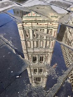 the reflection of a clock tower in a puddle