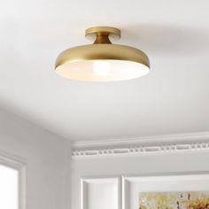 a ceiling light in a room with white walls and paintings on the wall behind it