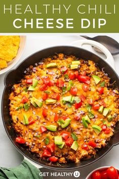 the healthy chili cheese dip in a skillet with tomatoes, avocado and cilantro