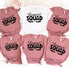 six t - shirts with sayings on them are sitting next to a pink flower