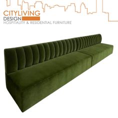 a green couch sitting on top of a white floor next to a tall city skyline