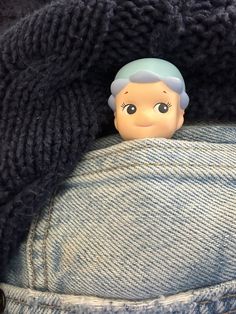 a small doll sticking out of the back pocket of someone's jean pants,