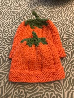 an orange knitted hat sitting on top of a bed