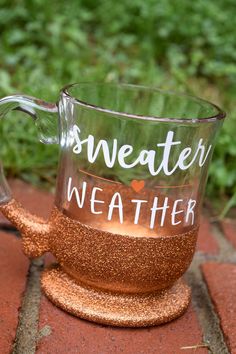 a glass mug with the words weather on it is sitting on a red brick surface