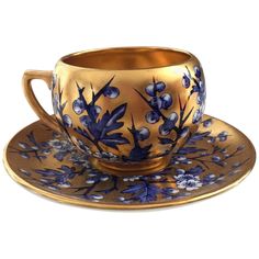 a golden cup and saucer with blue flowers on it