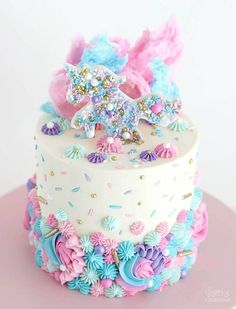 a white cake with pink, blue and purple frosting on the top is decorated with flowers