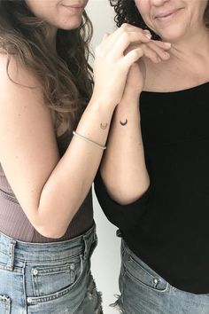 two women standing next to each other in front of a white wall with their arms crossed