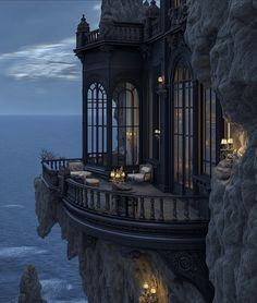 a balcony overlooking the ocean at night with candles lit up on it's balconies