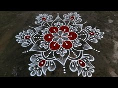 a white and red flower design painted on the ground by someone's hand,