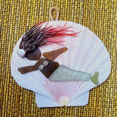 an assortment of sea glass on a white shell with long red hair hanging from it