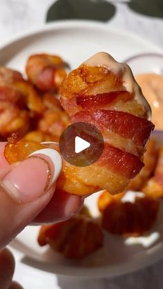 someone is holding up bacon rings on a plate