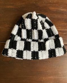 a black and white knitted hat sitting on top of a wooden table next to a pair of scissors