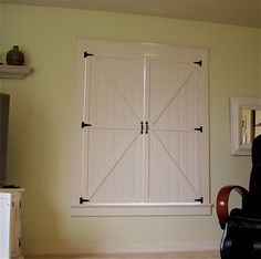 a living room with a chair, television and sliding barn doors on the wall above it