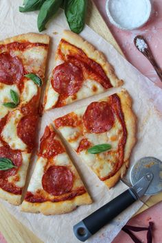 a pepperoni pizza cut into four slices on top of a cutting board with a spatula