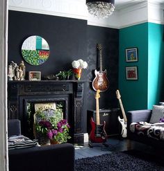 a living room filled with furniture and a guitar on top of a fireplace mantel