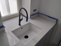 a white sink sitting under a window next to a faucet in a bathroom