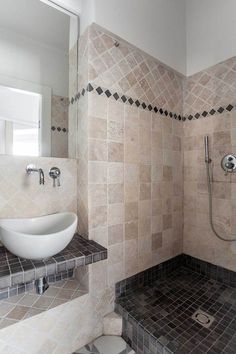 a bathroom with tiled walls and flooring in the shower area, along with a white bowl sink