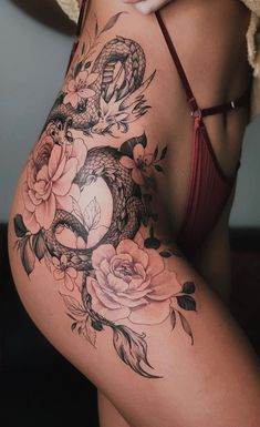 a woman's stomach with flowers and a snake tattoo on her side ribcage