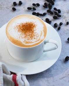 a cappuccino on a saucer with coffee beans scattered around the cup