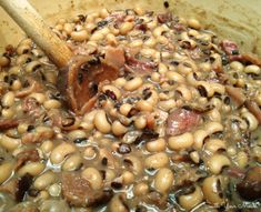 black eyed peas and ham in a pot with a wooden spoon