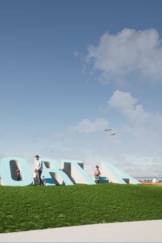 two people are standing in front of the word'zoo'on top of green grass