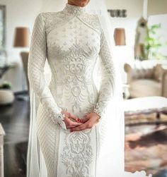 a woman in a white wedding dress standing next to a couch