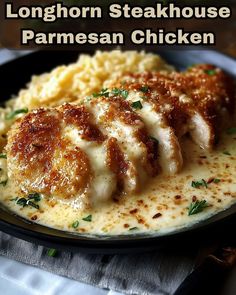 a black plate topped with mashed potatoes and chicken covered in grated parmesan cheese