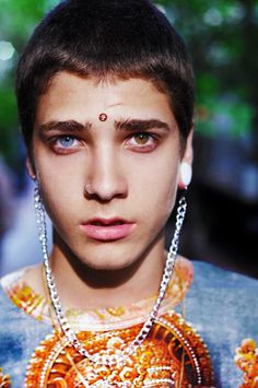 an image of a man with piercings on his forehead and wearing jewelry around his neck