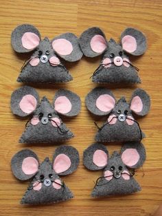 several mouses made out of felt on a wooden table with one wearing a pink nose