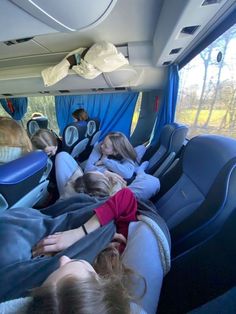 several people sleeping in the back of a bus with blue curtains on it's windows